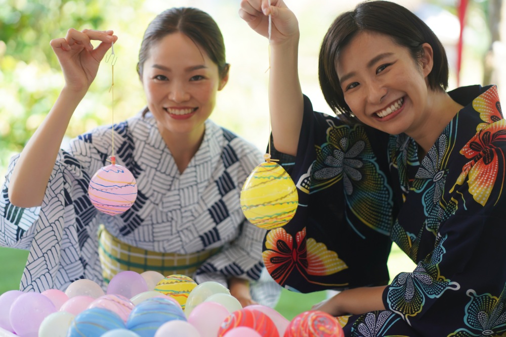 兩位穿著浴衣的女孩，在夏日祭典中開心展示釣到的水球。